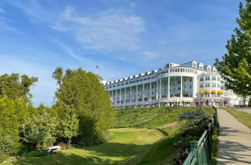 a large white building sitting on top of a lush green hillside